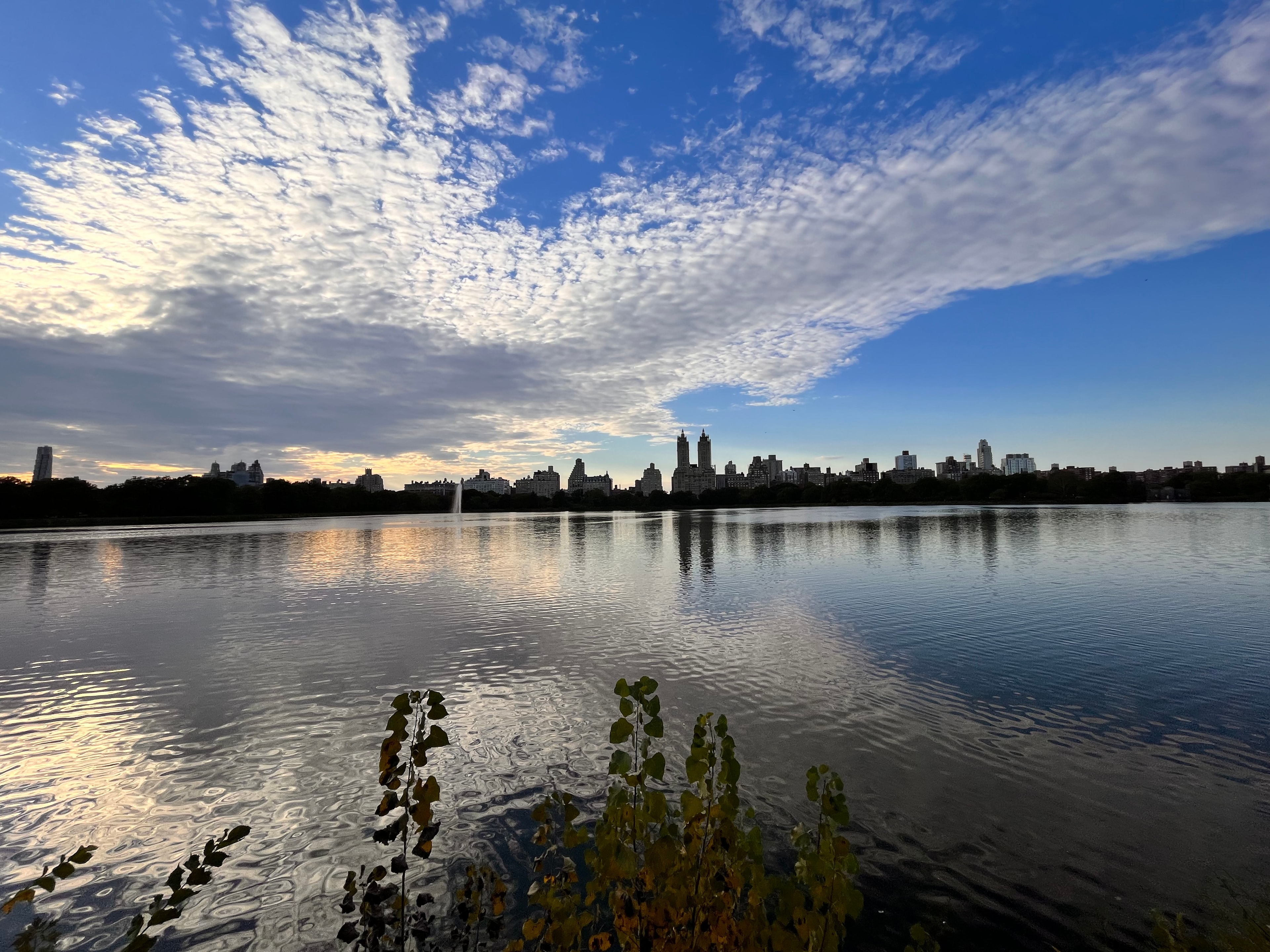 Central Park reservoir reflecting NYC skyline under a dramatic mackerel sky at dusk