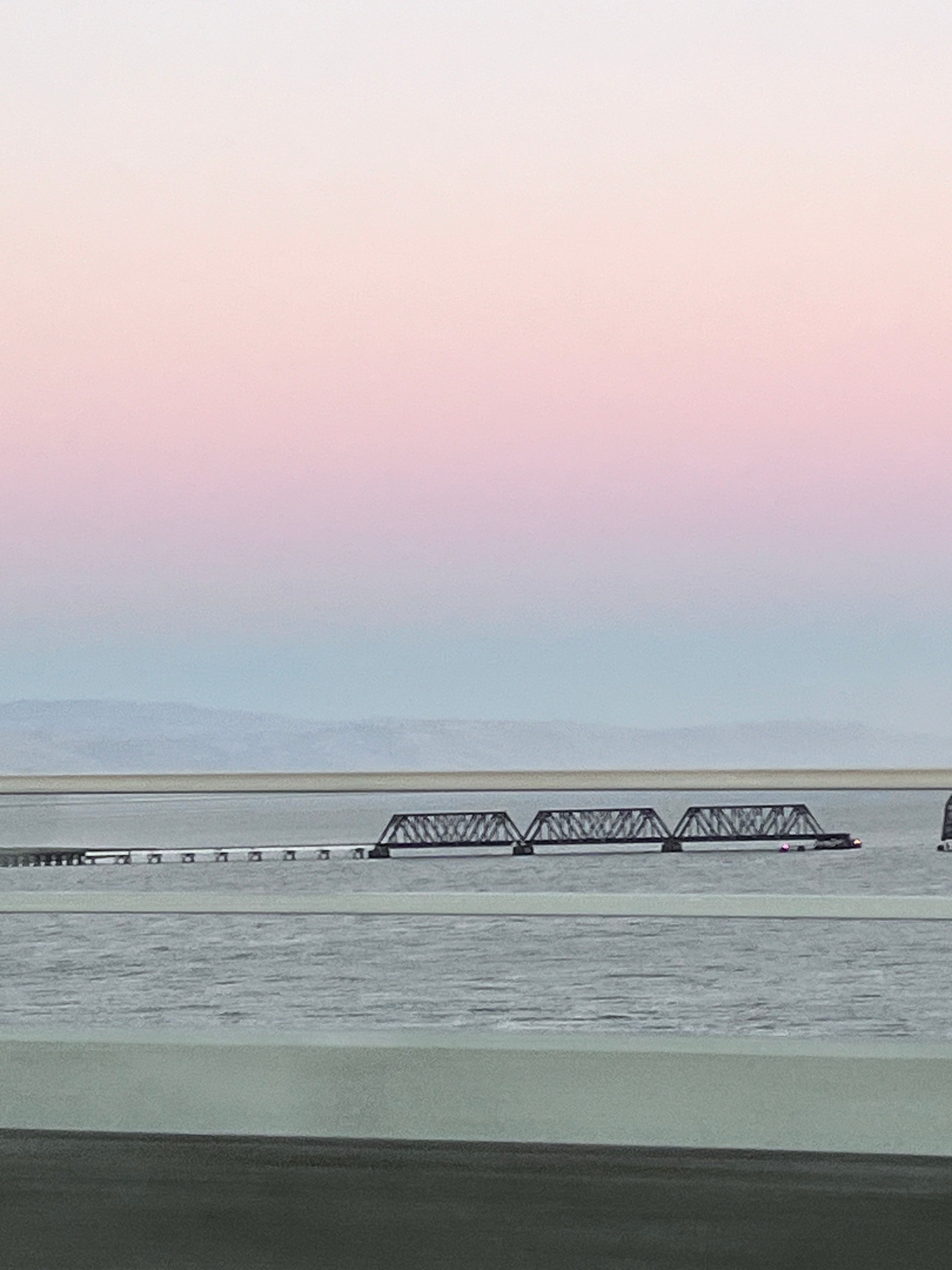 Sailboat on calm water under a soft pastel gradient sky