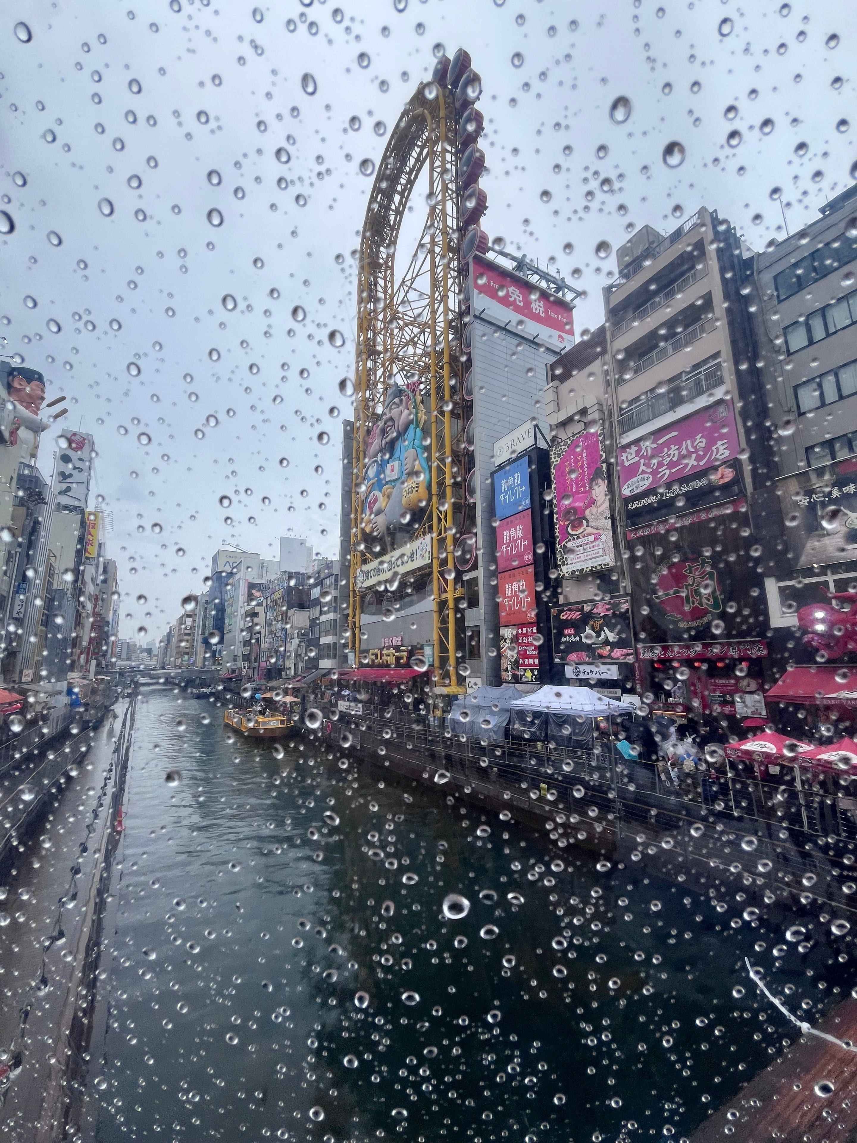Osaka Dotonbori canal and Ferris wheel through a rain-dotted window